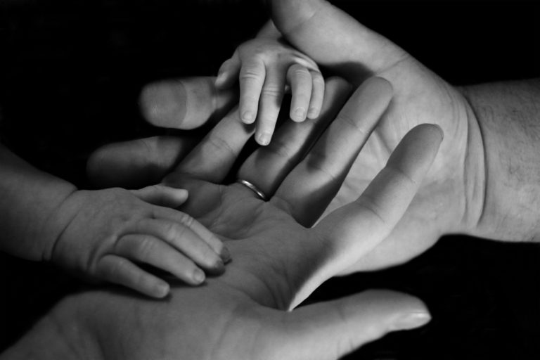 Closeup image of child's hands holding adult hands