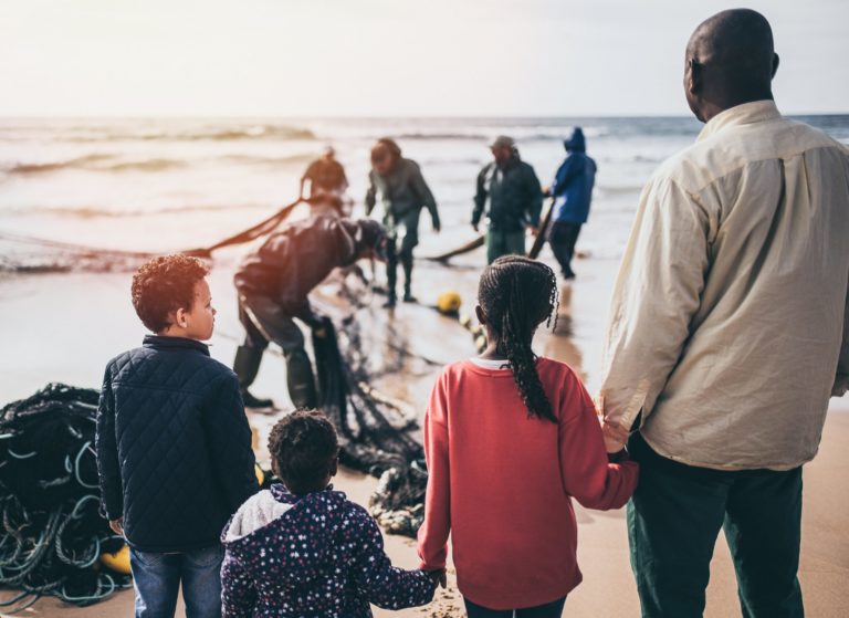 Image of a family walking hand and hand along a beach