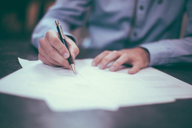 Image depicting a man's hands signing documents