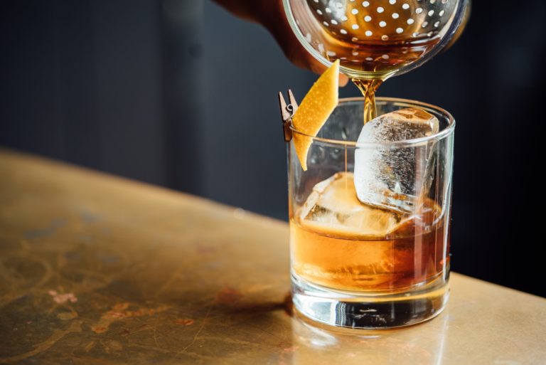 Image of whiskey sour being poured in a glass