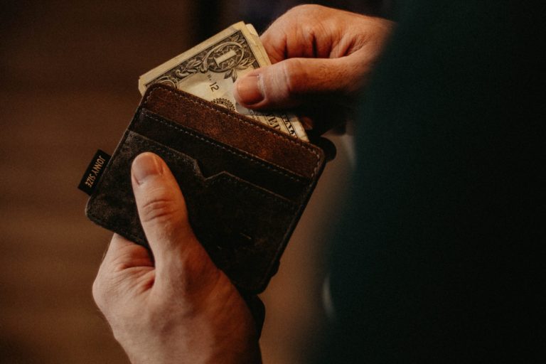 Closeup image of hands taking dollar bills out of a wallet