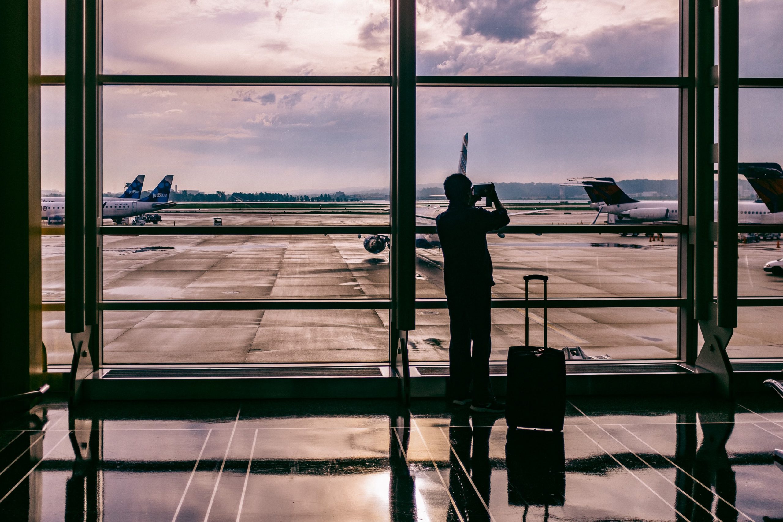 Image of a person silhouetted with suitcases in an airport terminal window
