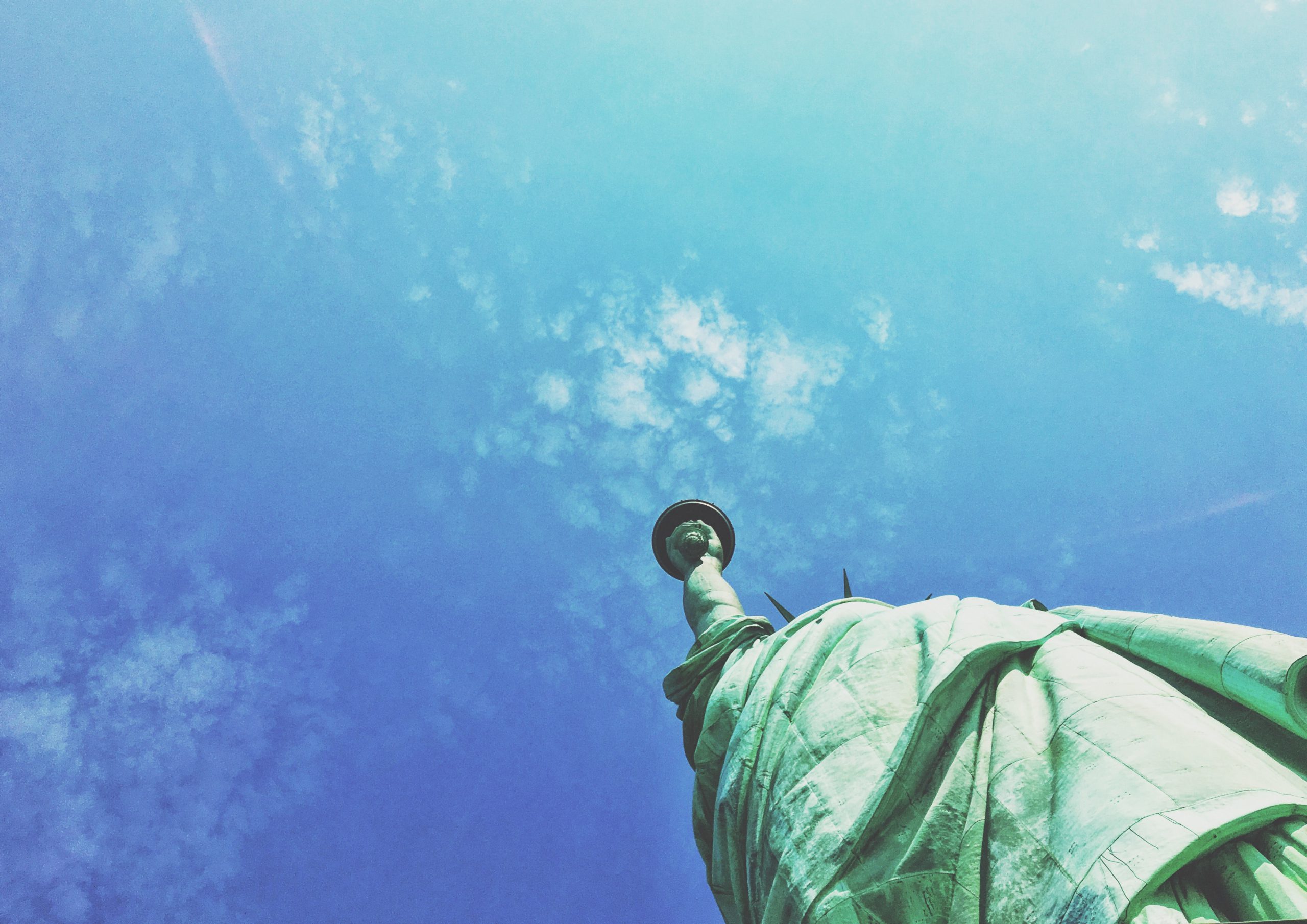 Shot from below - the statue of liberty against a blue sky.