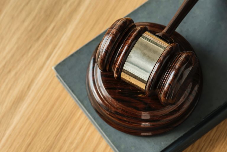 Image of a judge's gavel sitting on a table, up close