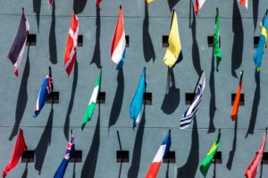Image of multiple national flags all set out next to each other outdoors on pavement.