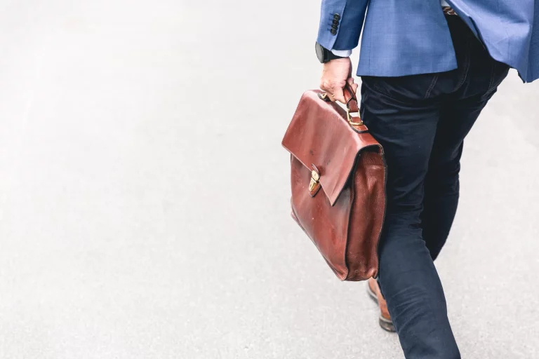 Meet the staff. Image of the lower half of a person holding a briefcase wearing a suit for a job. American worker immigration.