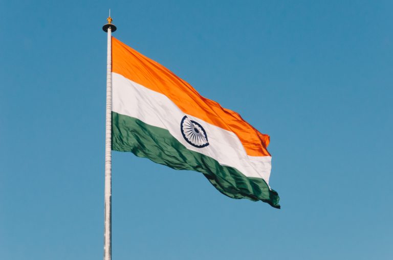 Indian Immigrant Surge at Border. Image of the Indian flag flying against a blue sky.