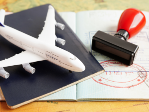 Ways to immigrate to the US. Image of stamp, passport, and toy plane on a table.