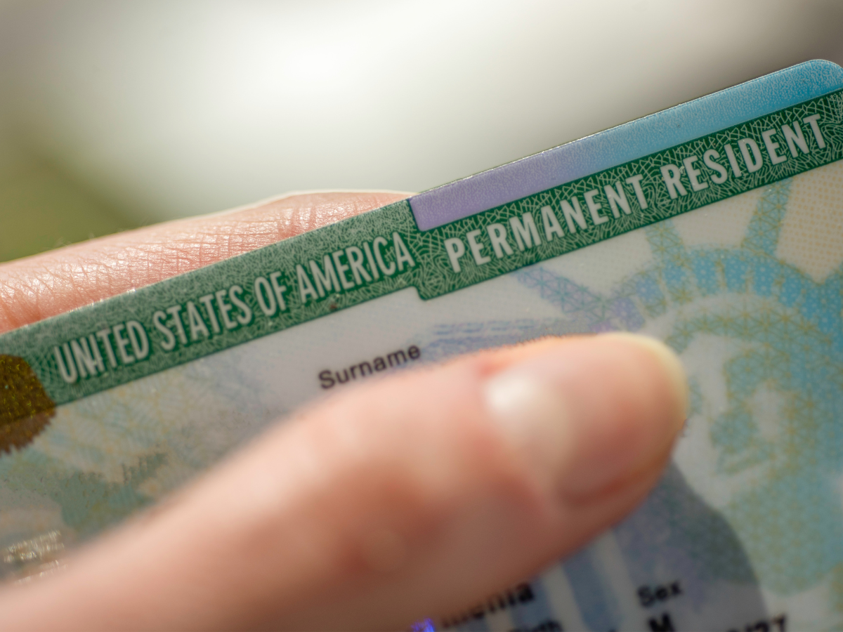 Hand holding a green card. Process for green card renewal.